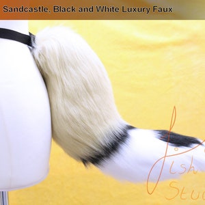 A luxury faux fur wild dog themed fursuit tail.

The base of the tail is sandcastle, tip is white. A black band seperates the two colours. There is also a black spot on the top of the white section. 

Great fur cosplays and costumes
