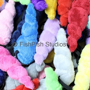 May include: A collection of colourful plush unicorn horn headbands. The headbands are made of soft, fuzzy fabric and come in a variety of colours, including pink, blue, purple, yellow, and green.