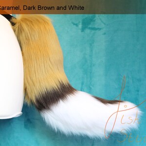 A luxury faux fur wild dog themed fursuit tail.

The base of the tail is caramel, tip is white. A dark brown band seperates the two colours. There is also a dark brown spot on the top of the white section. 

Great fur cosplays and costumes