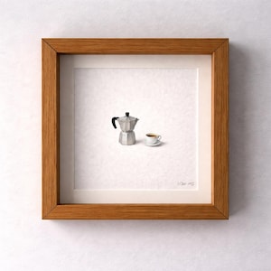 May include: A framed artwork depicting a miniature silver coffee pot and a small white teacup with coffee. The artwork is set against a white background and framed in a natural wood frame.