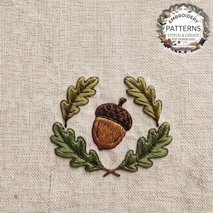 May include: An embroidery design on beige fabric featuring a central brown acorn surrounded by four green oak leaves. The top right corner includes a circular logo with the text EMBROIDERY PATTERNS STITCH & CREATE PDF DOWNLOAD BUY 3 GET 50% OFF.