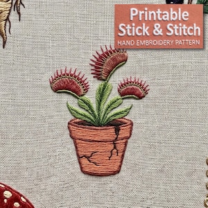 May include: An embroidery design on light beige fabric featuring a Venus flytrap plant with green leaves and red-tipped traps in a cracked terracotta-colored pot. The text "Printable Stick & Stitch HAND EMBROIDERY PATTERN" is visible in the corner.