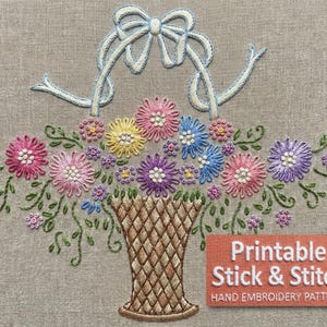 May include: Embroidered floral basket design with a light blue bow. The basket is filled with colorful flowers in shades of pink, yellow, blue, and purple. The text "Printable Stick & Stitch" is on a rectangular label.