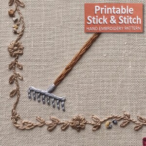 May include: A hand embroidery pattern on beige fabric featuring a brown rake with a silver head, surrounded by a brown floral vine border. The text reads: Printable Stick & Stitch HAND EMBROIDERY PATTERN.