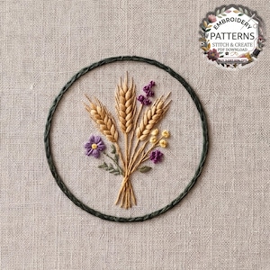 Op de afbeelding: Een ronde borduurring met een handgestikt ontwerp van drie gouden korenaren, kleine paarse bloemen en piepkleine gele knopjes op lichtbeige stof. Een rond logo rechtsboven bevat de tekst EMBROIDERY PATTERNS STITCH & CREATE PDF DOWNLOAD.