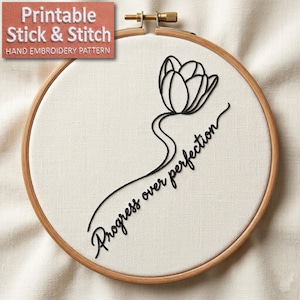 May include: A wooden embroidery hoop holds a cream-colored fabric with a black embroidered tulip design and the words "Progress over perfection." The top left corner features a label that reads "Printable Stick & Stitch Hand Embroidery Pattern."