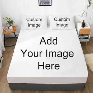 May include: A white bed with a fitted sheet and two pillowcases. The pillowcases have the text "Custom Image" printed on them. The fitted sheet has the text "Add Your Image Here" printed on it. The bed skirt is gray.