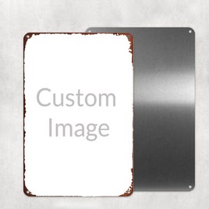以下が含まれることがあります： 中央が白く「Custom Image」という文字が書かれた、錆びた茶色の縁取りがある長方形の金属製看板。その背後には、もう一枚の無地の銀色の金属製看板が一部重なって配置されており、どちらの看板の四隅にも小さな穴が開いている。