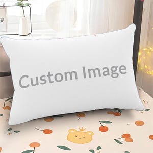 May include: A rectangular white pillow featuring the text Custom Image printed in gray across the center. The pillow rests on a light-colored surface decorated with a repeating pattern of small orange cherries and yellow bear faces with crowns.