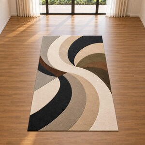 May include: A rectangular area rug featuring a large, sweeping S-shaped design. The pattern consists of curved, layered bands in a palette of black, cream, beige, tan, brown, and olive green, creating a dynamic, flowing visual effect on the floor.