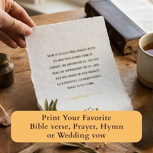 May include: A hand holds a piece of textured, off-white paper with a Bible verse printed in black ink. The text begins, "Now it is God..." A banner at the bottom reads, "Print Your Favorite Bible verse, Prayer, Hymn or Wedding vow."