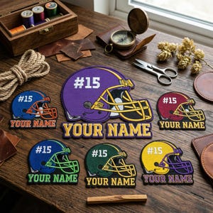 May include: A collection of embroidered football helmet patches in various colors, including purple, blue, maroon, green, and yellow. Each patch features the number "15" and the text "YOUR NAME" in a contrasting color. The helmets have gold or green face masks.