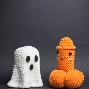 May include: Two handmade crochet figures against a dark backdrop. One is a white ghost with black eyes and mouth. The other is an orange figure with a hat, eyes, and a smiling face. Halloween-themed decorations.