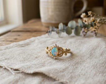 Anello di fidanzamento con opale ovale, dettagli floreali vintage in oro e diamanti, pietra portafortuna di ottobre ispirata alla natura.