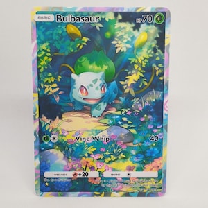 May include: A Bulbasaur Pokémon trading card featuring a blue and green creature in a forest setting. The card has the text "Bulbasaur", "Vine Whip", and "HP70". The card's border is a mix of colors.