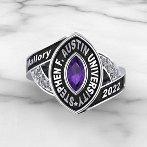 May include: A silver and black Stephen F. Austin University class ring with a purple centre stone. The ring features the name "Mallory" and the year "2022". The ring has a decorative design with small clear stones.