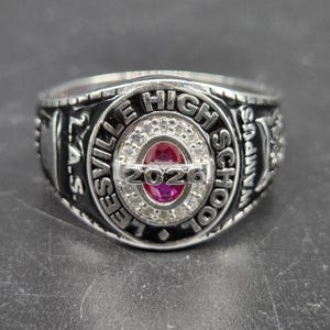 May include: A silver Leesville High School class ring. The ring features the words "LEESVILLE HIGH SCHOOL" and "2026" around a central red stone. The ring also has the letters "L.A.S." and "CAMPUS" on the sides.