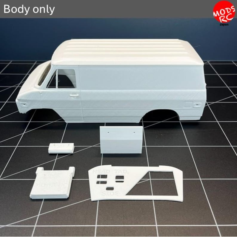 May include: A white 3D printed model van body shell with a ribbed roof and open window frames. Included are several separate white plastic components, including a flat rectangular piece, a small block, and a frame with text reading HEAD TAIL SIDE.