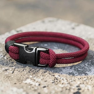 Puede incluir: Una pulsera de cuerda burdeos con un cierre de metal negro. La pulsera est&aacute; hecha de dos hebras paralelas de cuerda burdeos, aseguradas con un cierre de metal negro. El cierre tiene un dise&ntilde;o simple y funcional.