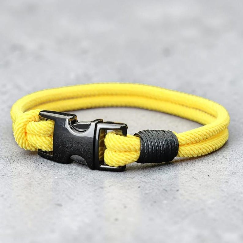 Puede incluir: Pulsera de cuerda amarilla con cierre negro y secci&oacute;n envuelta en negro. La pulsera est&aacute; hecha de un material de cuerda amarillo brillante y tiene un dise&ntilde;o simple y moderno. El cierre es una hebilla met&aacute;lica resistente.