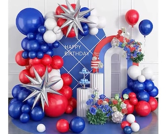 Puede incluir: Una escena festiva de cumpleaños con globos rojos, blancos y azules, decoraciones en forma de estrella y una tarta. El telón de fondo presenta las palabras "HAPPY BIRTHDAY" y un arco iris. Una exhibición vibrante y festiva.
