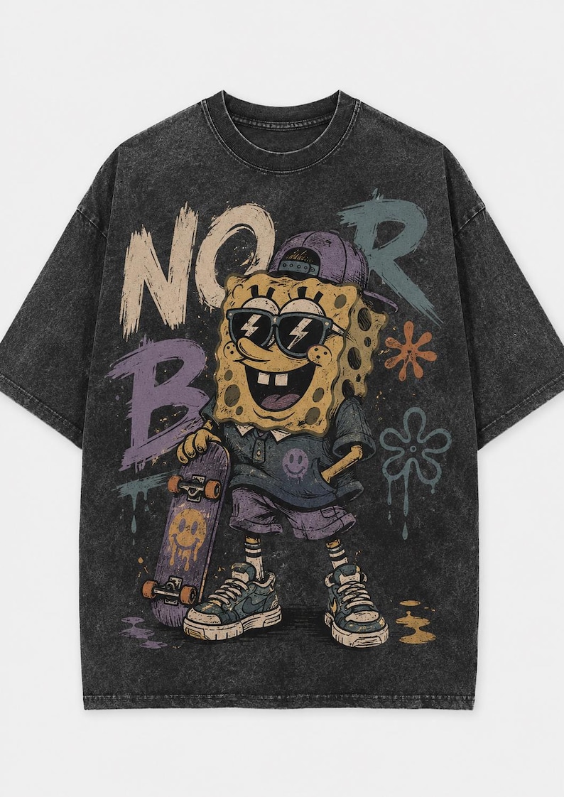 Puede incluir: Una camiseta gris carb&oacute;n con efecto lavado al &aacute;cido que presenta un gr&aacute;fico de un personaje de esponja amarillo con gorra morada y gafas de sol, sosteniendo un monopat&iacute;n. El dise&ntilde;o incluye el texto "NO R" y "B" en estilo grafiti.