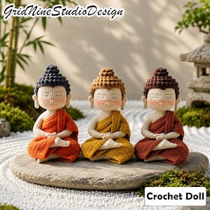 May include: Three crochet dolls in a seated meditation pose, each featuring a textured topknot, closed eyes, and pink cheeks. The dolls wear robes in orange, yellow, and reddish-brown, with cream-colored skin and matching hair colors.
