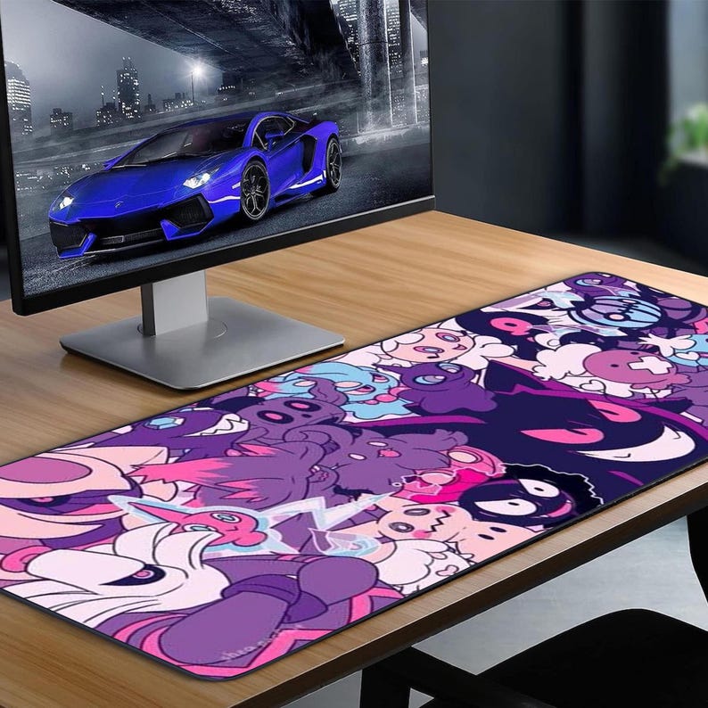 May include: A long, rectangular mouse mat with a vibrant cartoon design in shades of purple, pink, and white. The mat is placed on a wooden desk, with a computer monitor showing a blue sports car in the background.