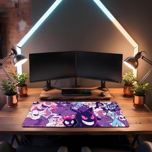 May include: A rectangular mouse mat with a vibrant design of cartoon characters in purple, pink, and blue. The mat sits on a wooden desk, with two computer monitors, a keyboard, and desk lamps in the background. The desk is made of wood.