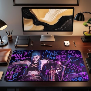 May include: A rectangular desk mat featuring a character illustration with blue hair and a dark outfit. The design includes neon blue and purple graffiti-style text and star shapes on a black background. The text includes "HAHA", "POW", and "BOOM".