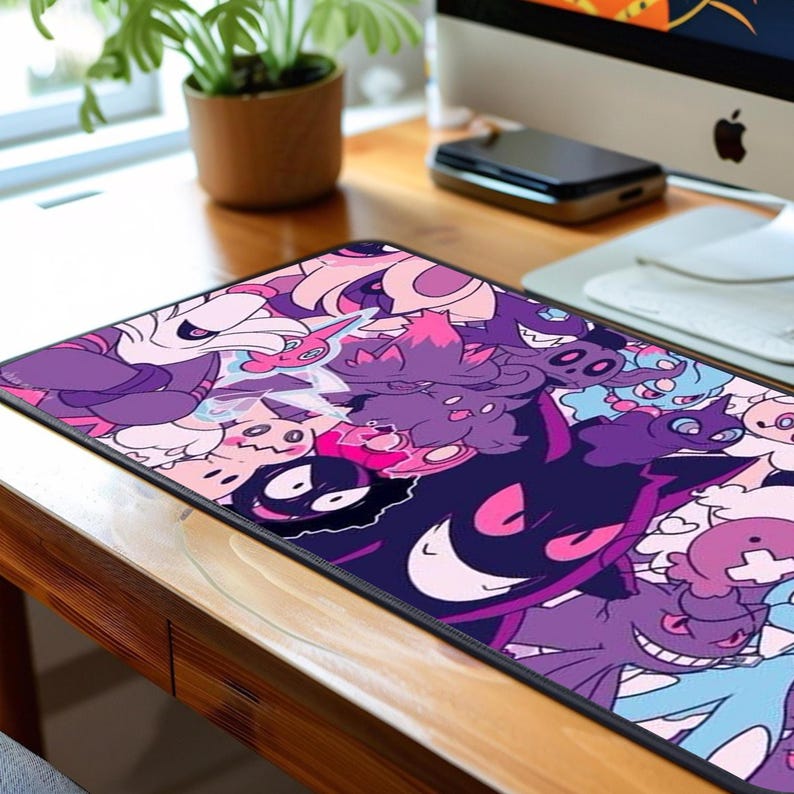 May include: A rectangular mouse mat with a cartoon design in purple, pink, and blue. The design features various characters. The mat is on a wooden desk, with a computer and other items in the background.
