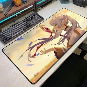 Op de afbeelding: Een rechthoekige muismat met een anime-stijl illustratie van een personage met lang wit haar en puntige oren. Het personage houdt een staf vast met een roze edelsteen. De achtergrond is een zachte, kleurrijke lucht met blauwe bloemblaadjes.