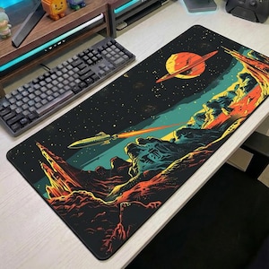 May include: A black rectangular mouse mat with a retro sci-fi space scene. The design includes a planet with rings, a spaceship firing a laser, and a colourful landscape. The mouse mat is designed for use with a computer.