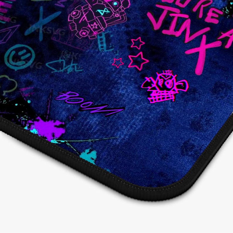 May include: A blue mousepad with a black border, featuring graffiti-style art in neon pink, purple, and teal. The design includes text and various graphic elements, creating a vibrant and energetic aesthetic.