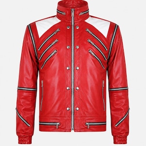 Puede incluir: Una chaqueta de cuero rojo brillante con paneles blancos en los hombros, cuello alto y múltiples cremalleras de metal plateado en el pecho y las mangas. El cierre frontal incluye una cremallera central y una fila vertical de botones a presión plateados.