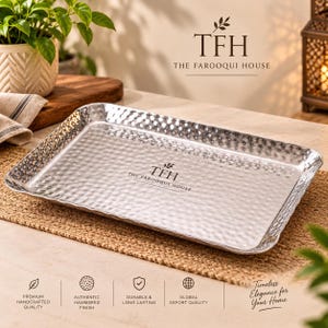May include: A rectangular silver-toned metal serving tray with a hammered texture finish. The center of the tray features the black printed text TFH THE FAROOQUI HOUSE. The tray has raised edges and a reflective, metallic surface.