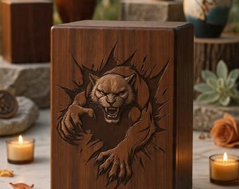 May include: A rectangular dark brown wooden urn featuring a detailed relief carving of a snarling panther emerging from the center. The wood grain is visible across the surface, and the carving depicts the animal with sharp claws and teeth.