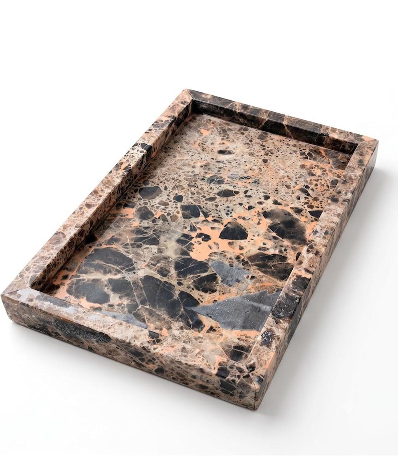 May include: A rectangular tray featuring a polished stone surface with a complex, multi-tonal pattern of black, dark brown, and soft peach-colored fragments. The tray has raised, thick edges and a smooth, glossy finish throughout the entire piece.