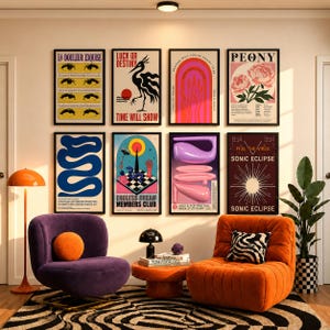 May include: A gallery wall featuring eight framed posters with diverse graphic designs, including text, abstract shapes, and illustrations, arranged above a purple armchair, an orange armchair, and a small orange coffee table on a patterned rug.