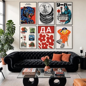 Può includere: Una parete galleria con sei poster incorniciati sopra un divano nero capitonné. Le opere includono una pantera blu, una pila di monete, uno scheletro conduttore radiofonico, icone di ispirazione giapponese e una stampa floreale rossa con il testo DA.