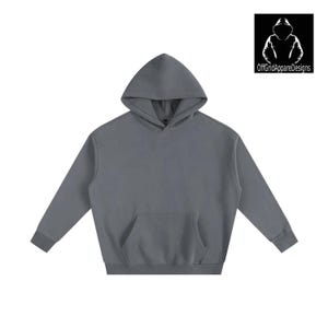 以下が含まれることがあります： カンガルーポケットとフードが付いたグレーのパーカー。長袖のスウェットシャツは無地で、ゆったりとしたフィット感です。OffGridAppareDesignsのロゴが右上隅にあります。