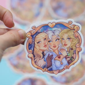 May include: A sticker featuring three women with long blonde hair. The women are wearing colourful outfits and are framed in a gold ornate frame with a heart at the top. The background is a light blue with stars.