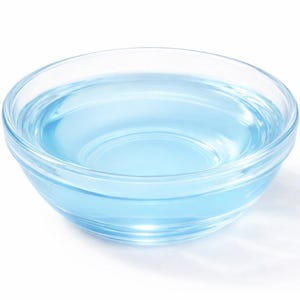 May include: A clear glass bowl filled with a translucent light blue liquid. The bowl features a smooth, rounded design with a thick base and curved sides, containing the liquid which reflects light across its surface against a white background.