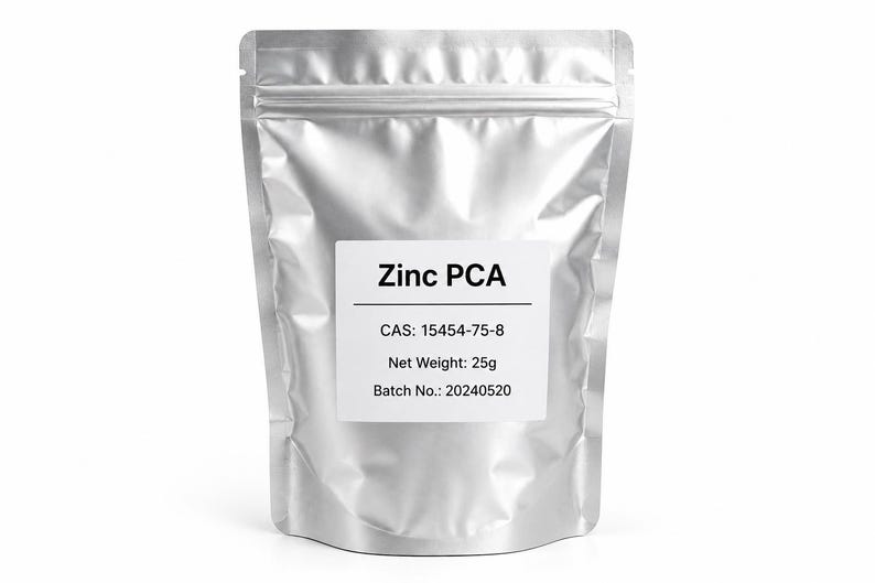 May include: A silver-colored, stand-up resealable pouch containing Zinc PCA. A white label on the front displays the text: Zinc PCA, CAS: 15454-75-8, Net Weight: 25g, and Batch No.: 20240520. The pouch has a matte metallic finish.
