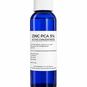 May include: A cobalt blue plastic bottle with a white screw cap and a white label. The label reads ZINC PCA 5% ACTIVE CONCENTRATE, lists ingredients, CAS 15454-75-8, Lot ZPCA-01, MFG 08/24, and states NET CONTENTS: 2 FL OZ (59 mL) for cosmetic use only.