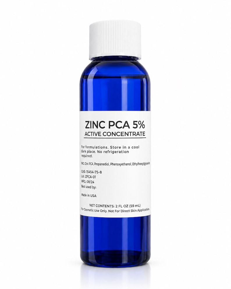 May include: A cobalt blue plastic bottle with a white screw cap and a white label. The label reads ZINC PCA 5% ACTIVE CONCENTRATE, lists ingredients, CAS 15454-75-8, Lot ZPCA-01, MFG 08/24, and states NET CONTENTS: 2 FL OZ (59 mL) for cosmetic use only.