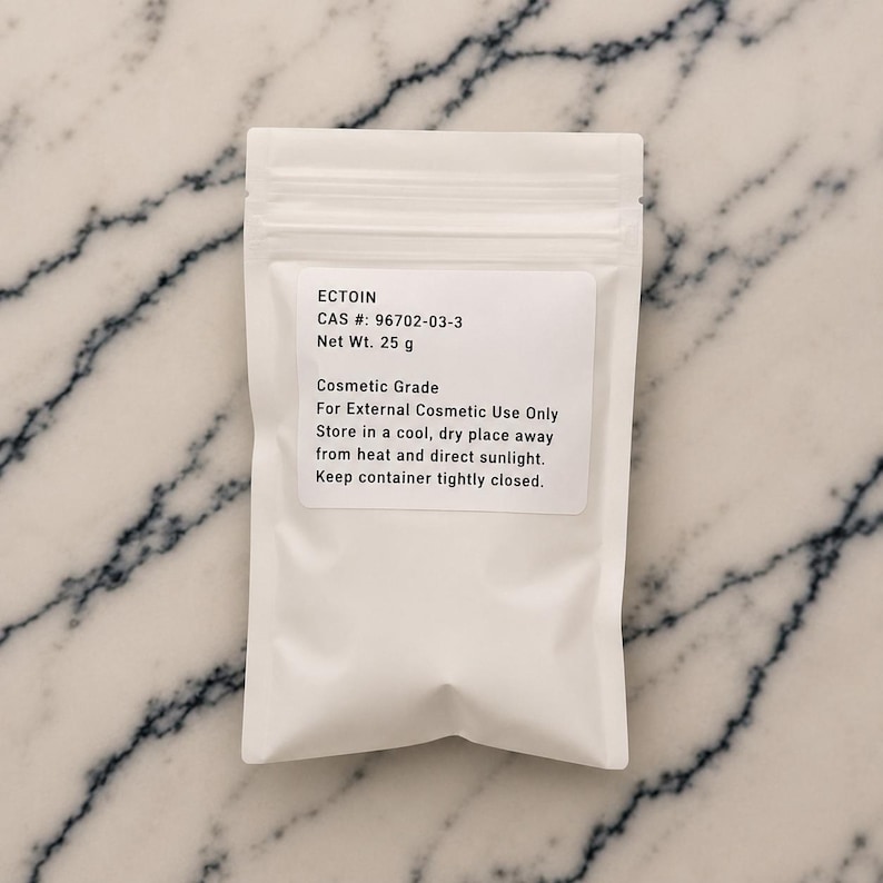 May include: A white, opaque, resealable plastic pouch containing 25 g of Ectoin. The label reads: ECTOIN, CAS #: 96702-03-3, Net Wt. 25 g, Cosmetic Grade, For External Cosmetic Use Only, Store in a cool, dry place away from heat and direct sunlight.