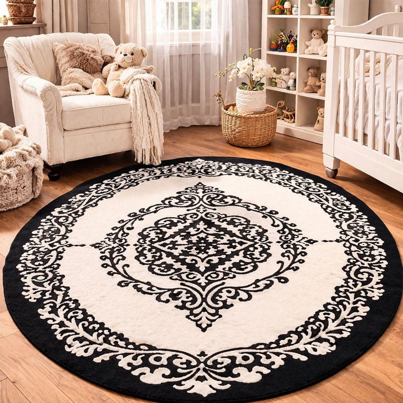 May include: A large circular area rug featuring a cream-colored background with a bold black damask pattern. The design consists of a central ornate medallion surrounded by a wide black border with intricate scrolling floral motifs.