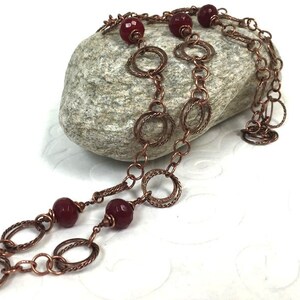 May include: A copper chain necklace with multiple linked circles and red gemstone beads.
