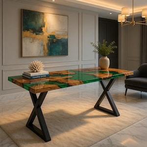 May include: A modern dining table with a green epoxy resin top and a natural wood grain design. The table has black metal X-shaped legs. A vase with greenery sits on the table. The room has a painting and a gray armchair.